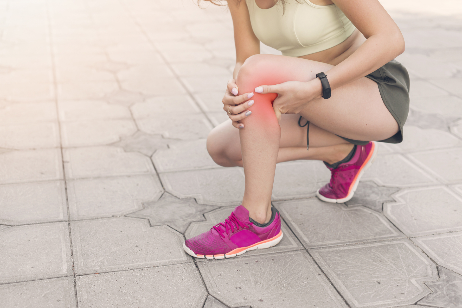 female athlete crouching pavement having pain knee