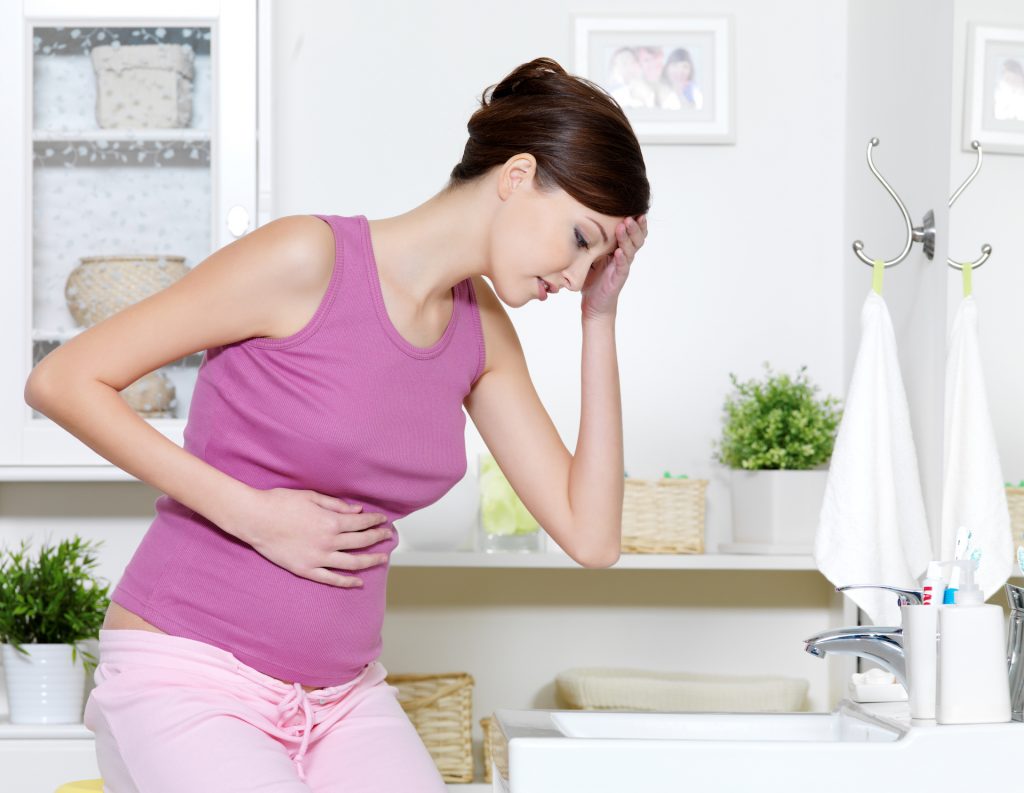 pregnant woman with strong pain stomach nausea sitting bathroom
